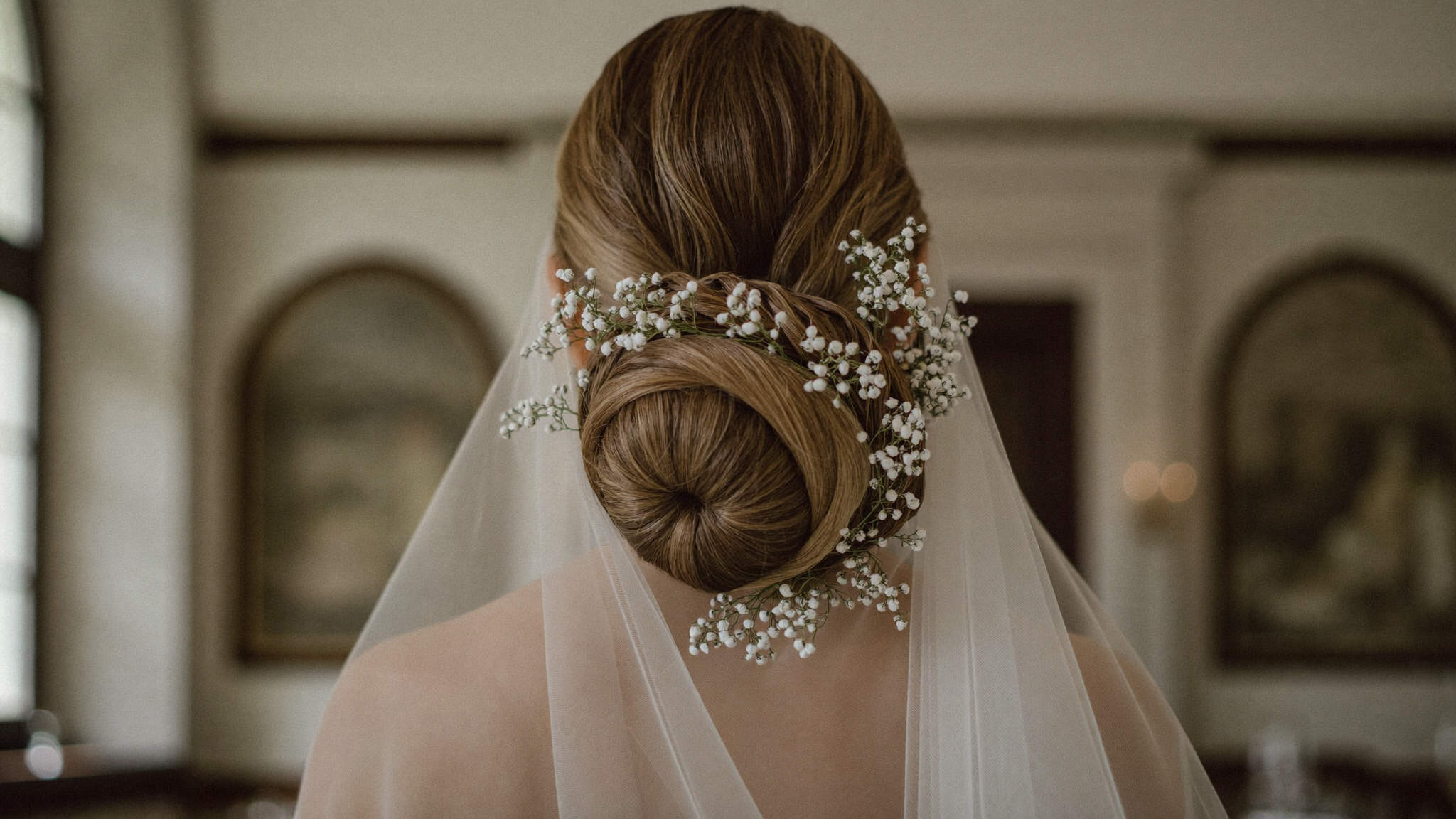 Bride with an intricate sculpted low chignon woven with baby's breath